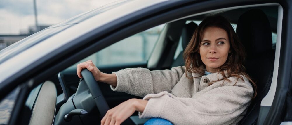 woman in gray sweater and blue denim jeans sitting on car seat