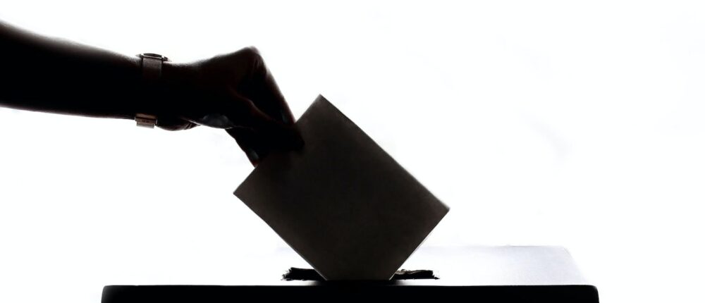 a person is casting a vote into a box
